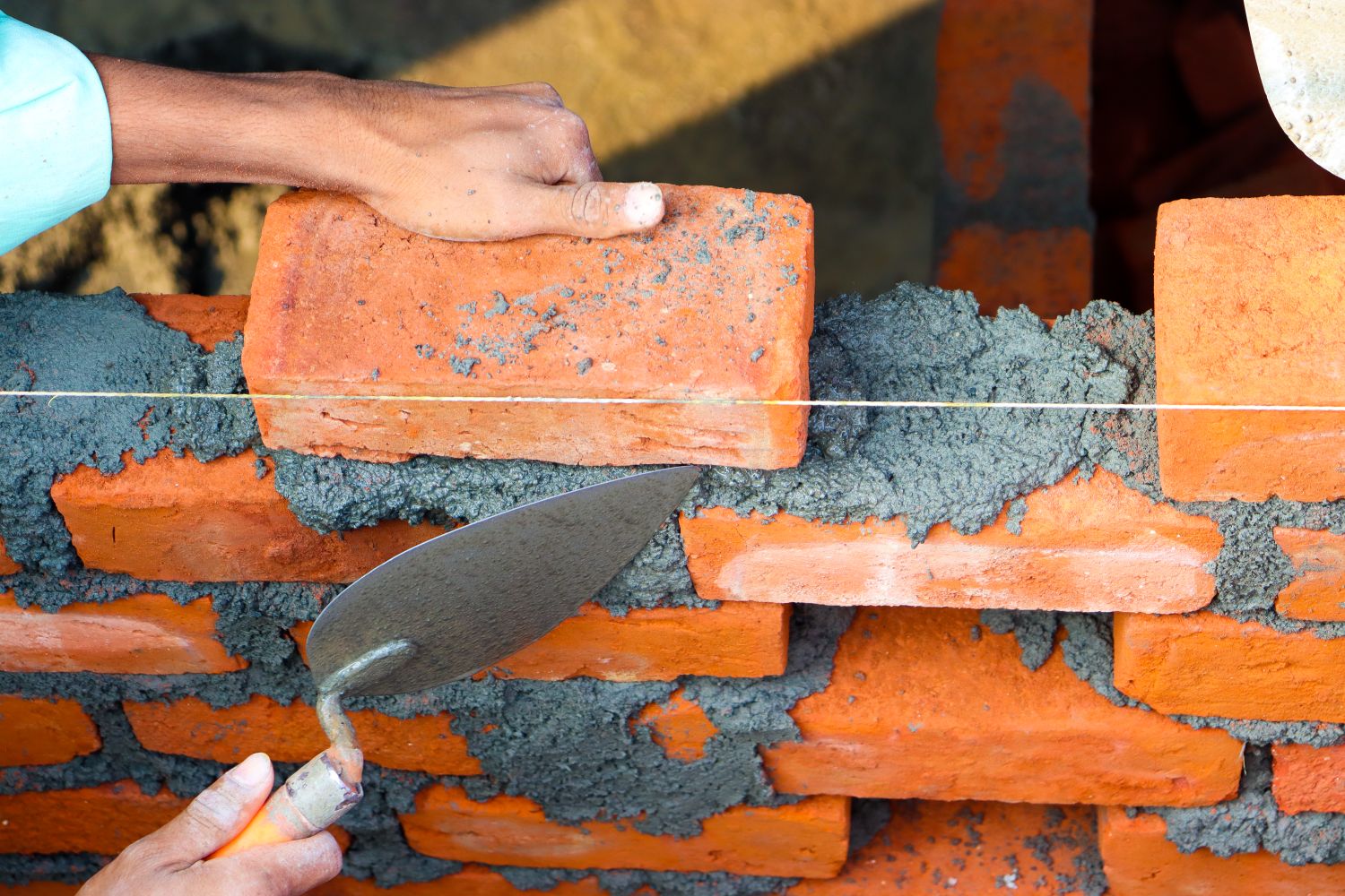 Mason carefully laying brick and mortar